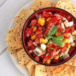 Closeup overhead photo of a bowl of Homemade Salsa with Tomatoes and Mango surrounded by tortilla chips