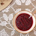 A serving bowl of cranberry sauce from above on a lace tablecloth