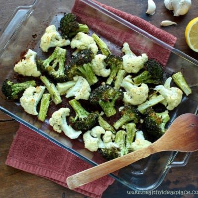 Broccoli and Cauliflower with Lemon and Garlic in a clear baking dish with a wooden spoon