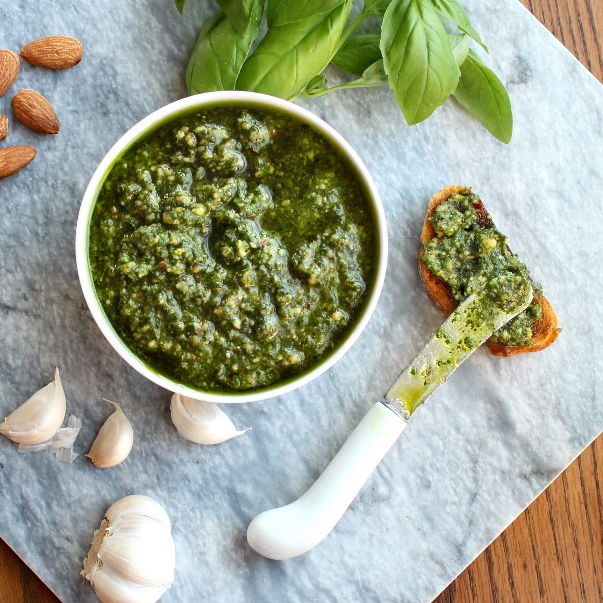 Basil Pesto with Almonds being spread on a crostini
