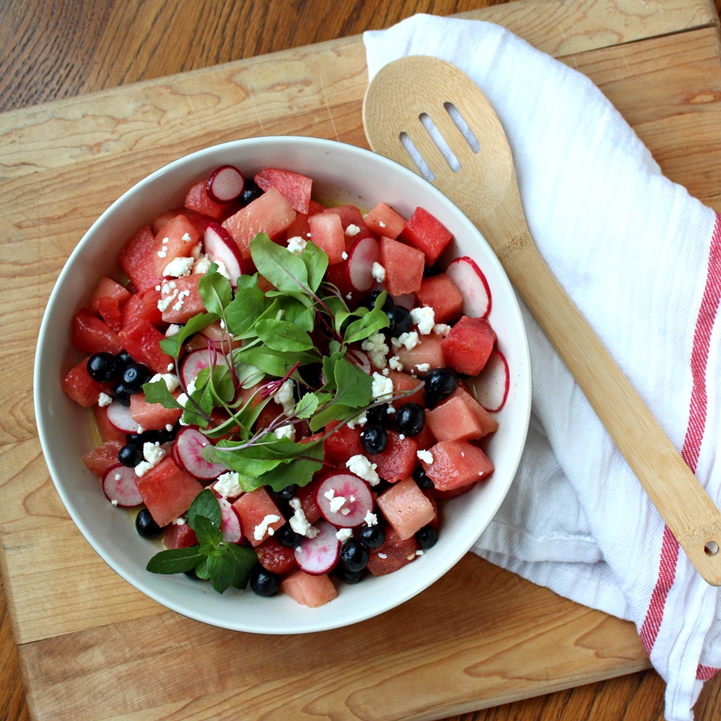 Watermelon, Blueberry, & Radish Salad in a serving bowl with a spoon and towel on the side