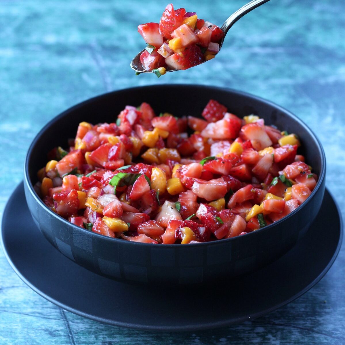 Strawberry Salsa in black bowl against a bluish background