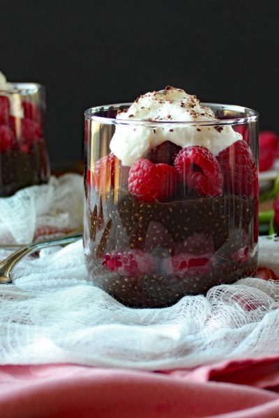 Closeup of Dark Chocolate Chia Seed Pudding with Raspberries in a clear glass