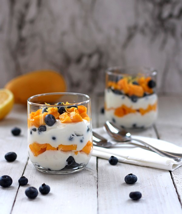 Diced mango and fresh blueberries layered with plain Greek yogurt in a clear glass