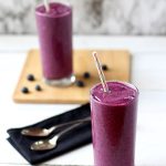 Blueberry banana smoothies in clear glasses with straw