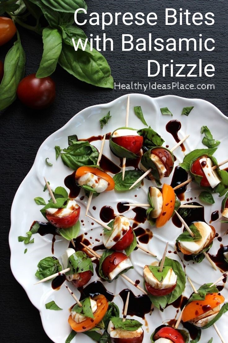 fresh basil leaves wrapped around cherry tomatoes and mozzarella on white plate