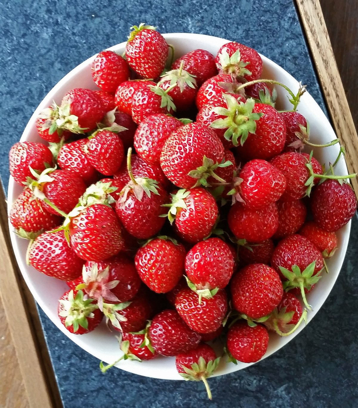 Strawberries in a white bowl on a gray backbround