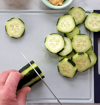cucumbers being sliced on a cutting board